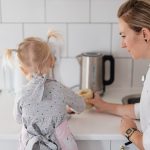 A mother helps her young daughter bake on a kitchen counter, creating a precious bonding moment.
