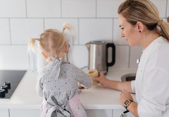 A mother helps her young daughter bake on a kitchen counter, creating a precious bonding moment.